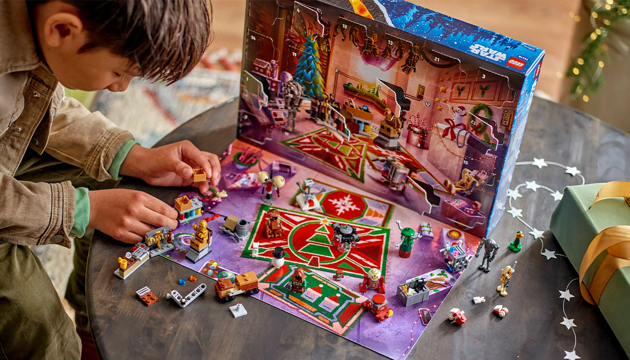 A child playing with the LEGO® droid minifigures next to the LEGO® Star Wars™ Advent Calendar 2025.png