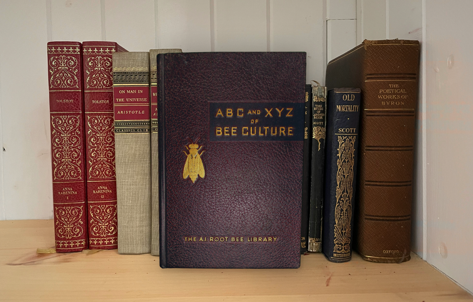 A collection of old books on a shelf including The ABC and XYZ of Bee Culture.png