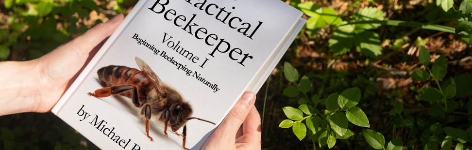 A person holding a copy of The Practical Beekeeper banner image.png