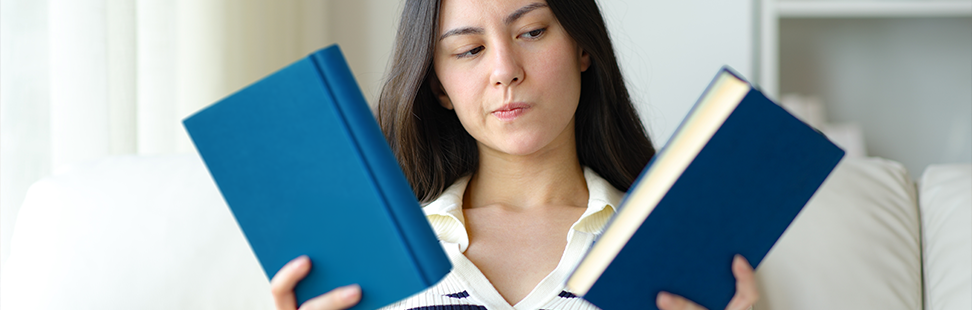 A woman choosing between two blue books.png
