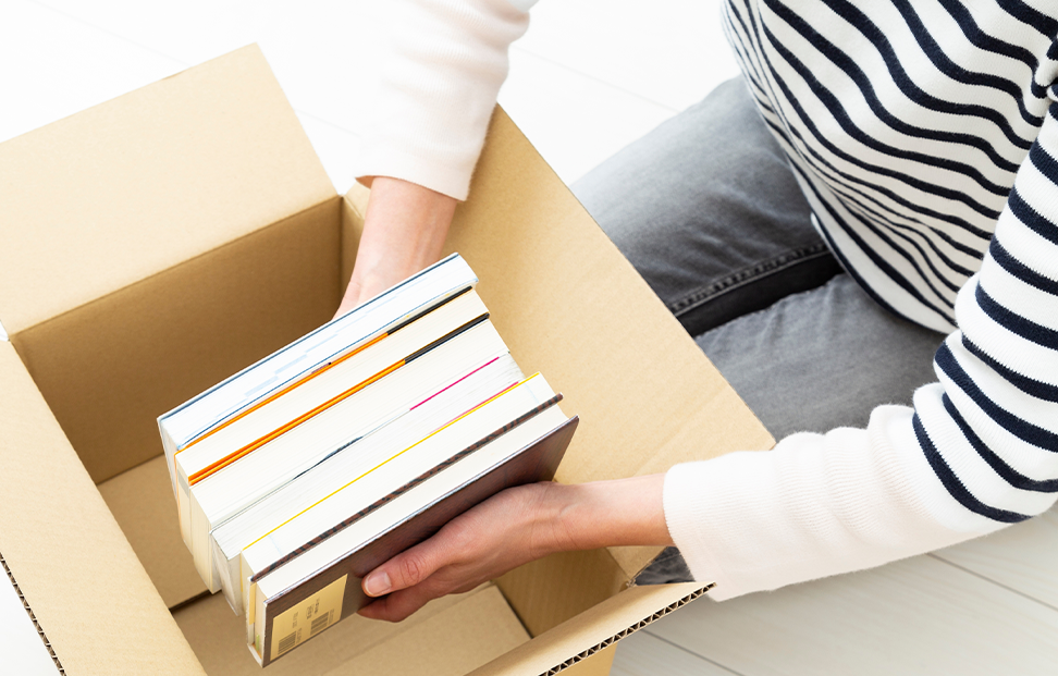 A woman filling a carboard box with old books.png