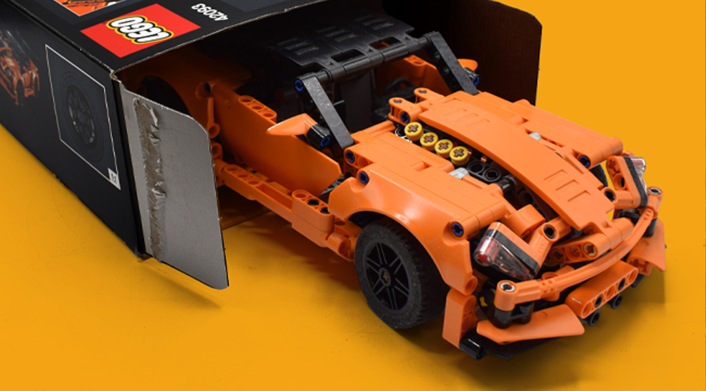 An orange LEGO® car coming out of a box.png