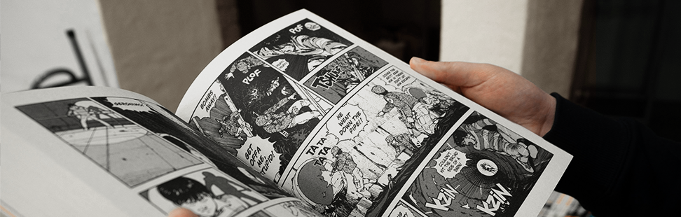Person in a black jumper reading an open manga.png