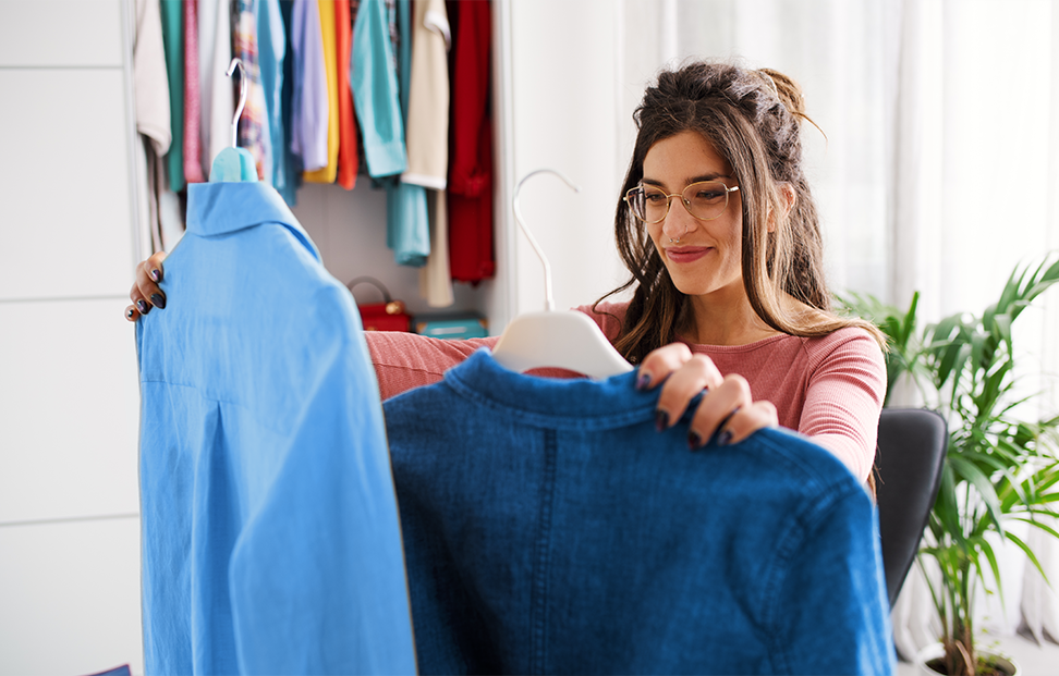 a woman choosing clothes for the One-In-One-Out Rule decluttering method.png