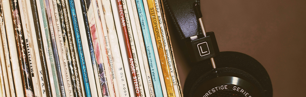 pair of vintage headphones next to a stack of vinyl records.png